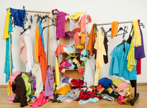 Untidy cluttered woman wardrobe with colorful clothes and accessories.