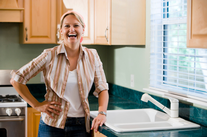 Portrait of a cheerful mid adult woman standing by kitchen counter